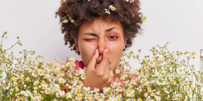 Woman sneezing surrounded by wildflowers